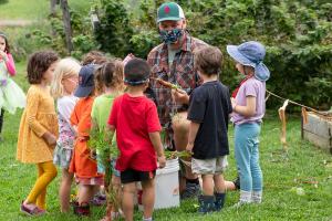 Students gather around an early childhood educator in the garden at Shelburne Farms