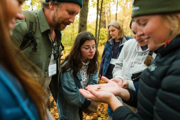 teachers in the forest observing a small object in palm of instructor